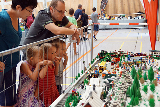 Erwachsene und Kinder bestaunen eine Lego-Landschaft