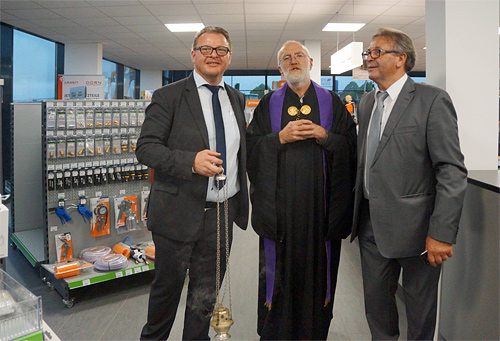 Foto von Pfarrer Josef Helm mit den Betriebsinhabern in den neuen Räumen