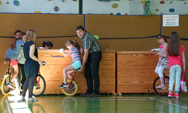 Kinder auf Einrädern, die sich am Kisten festhalten