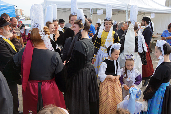 Bretonische Frauen mit Tracht, die aus Dirndl-ähnlichen Kleidern und hohen zylindrischen Hauben aus weißer Spitze besteht