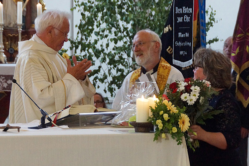 Pfarrer J. Helm und Chrstine Banse mit Blumenstrauß beim gratulieren